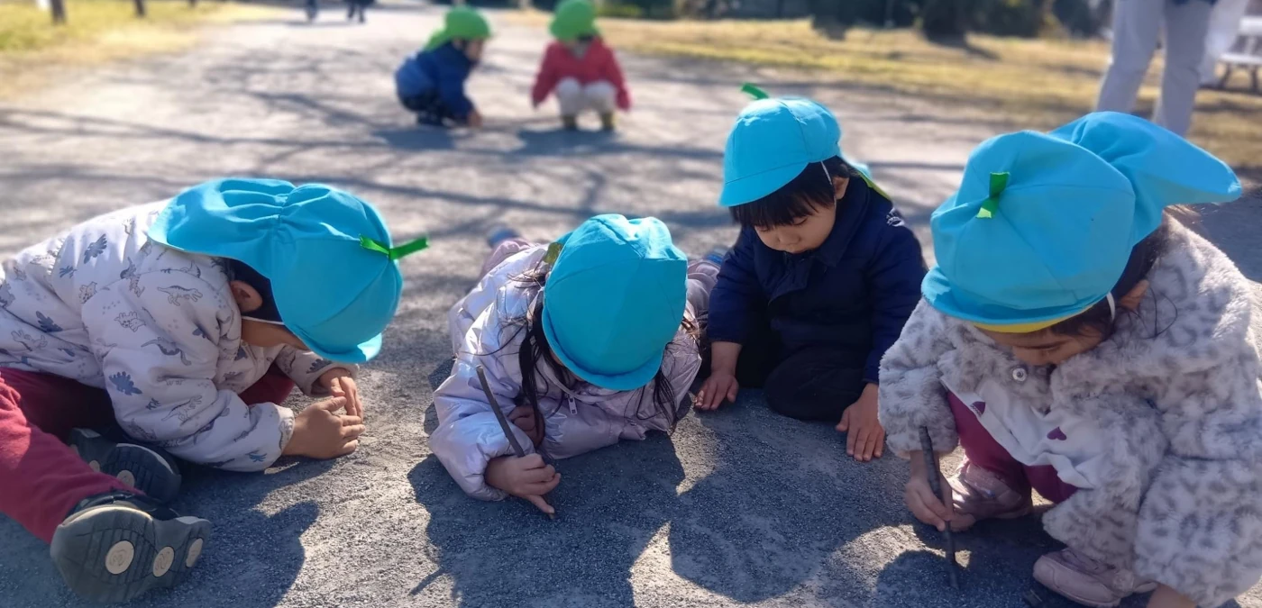 木の枝で砂利道に絵を描く子供たち