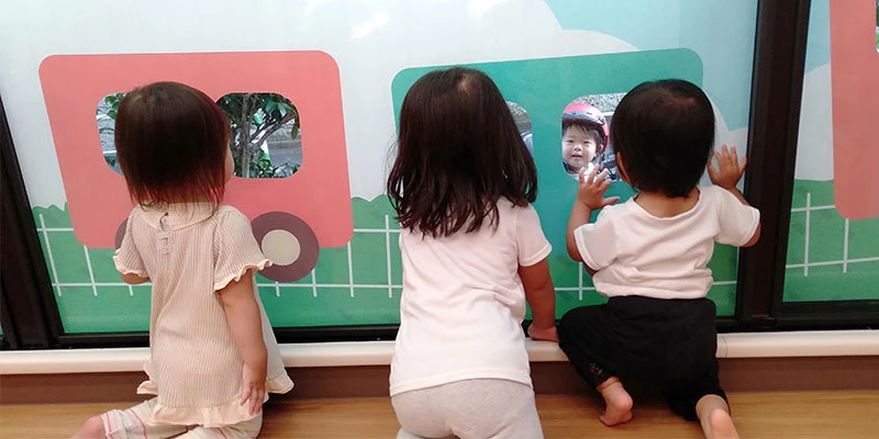 窓ガラスに貼った電車シールの窓を除く子供たち